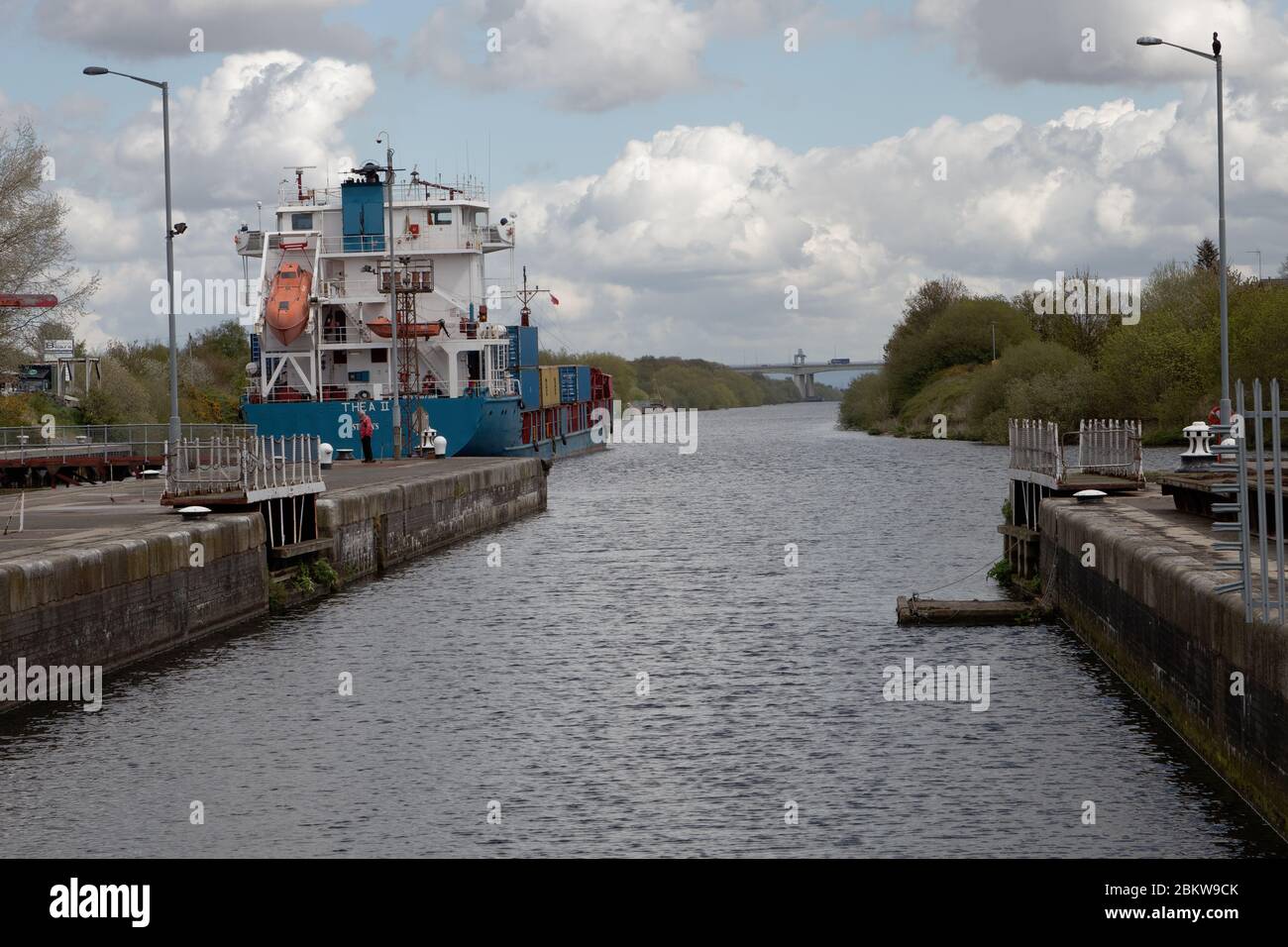 An ocean-going ship leaving Latchford Locks on the Manchester Ship Canal in Warrington with the Thelwall Viaduct on the M6 in the distance Stock Photo