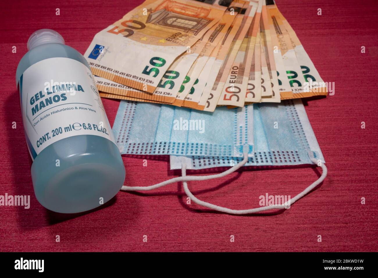 Billetes en euros, protección contra virus de máscara azul y frasco de gel Stock Photo