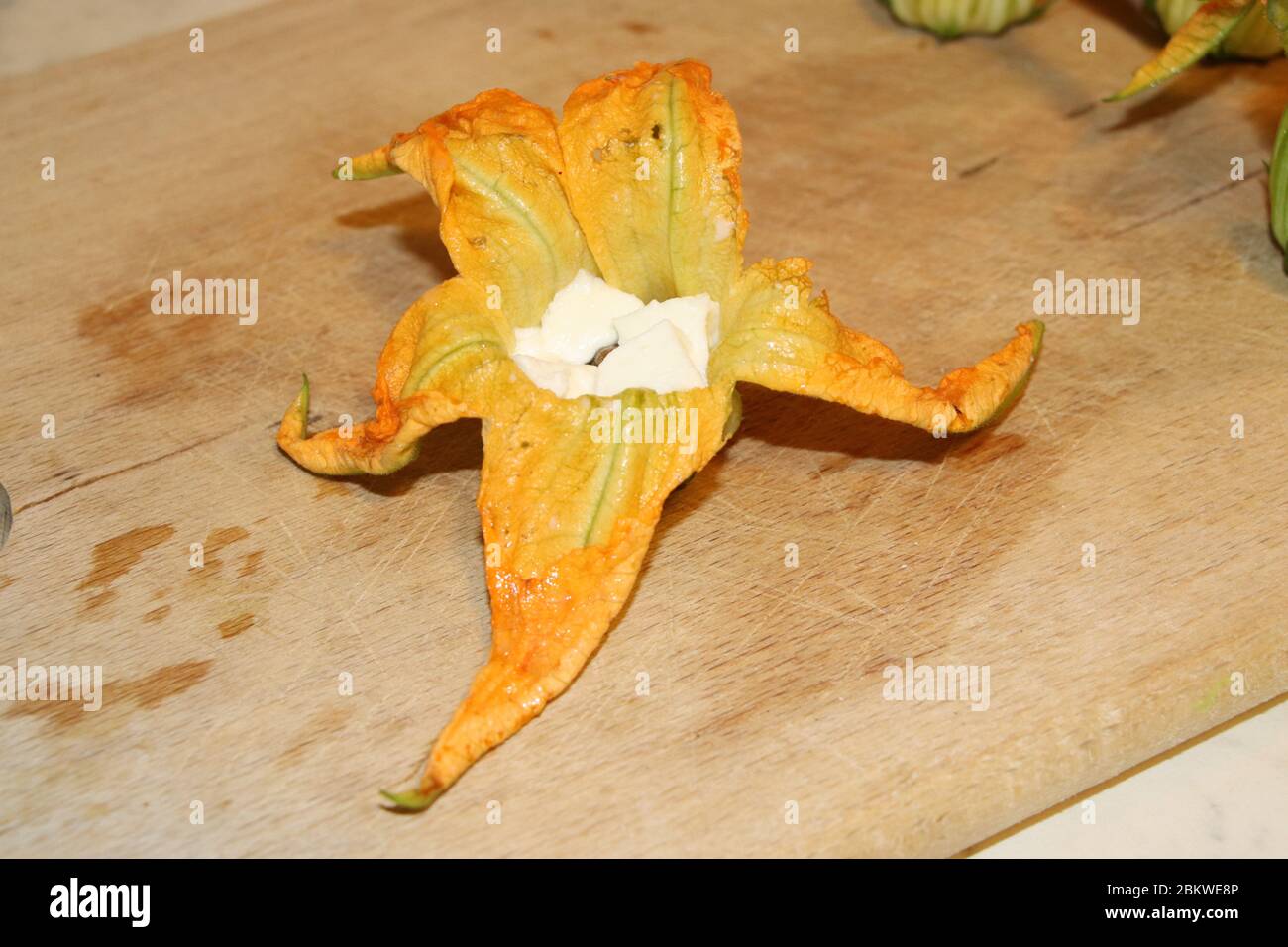preparation of zucchini flowers in batter with mozzarella and anchovies