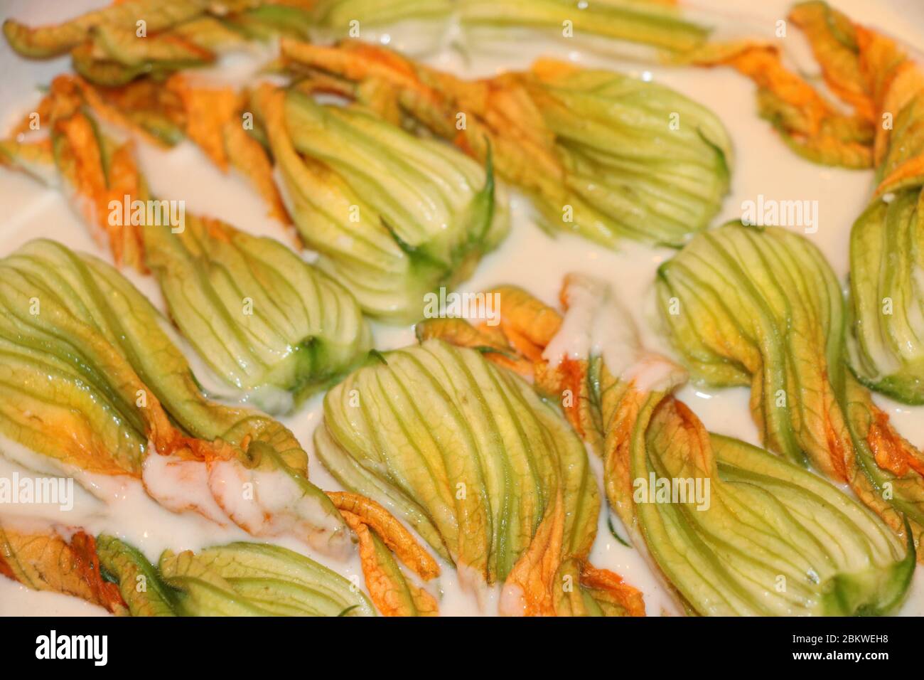 preparation of zucchini flowers in batter with mozzarella and anchovies