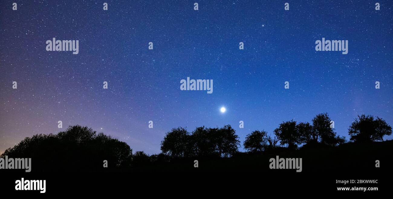 Multitude of stars and a shooting star in night sky with Venus at its brightest stage this year in prominent view over southern England, United Kingdo Stock Photo