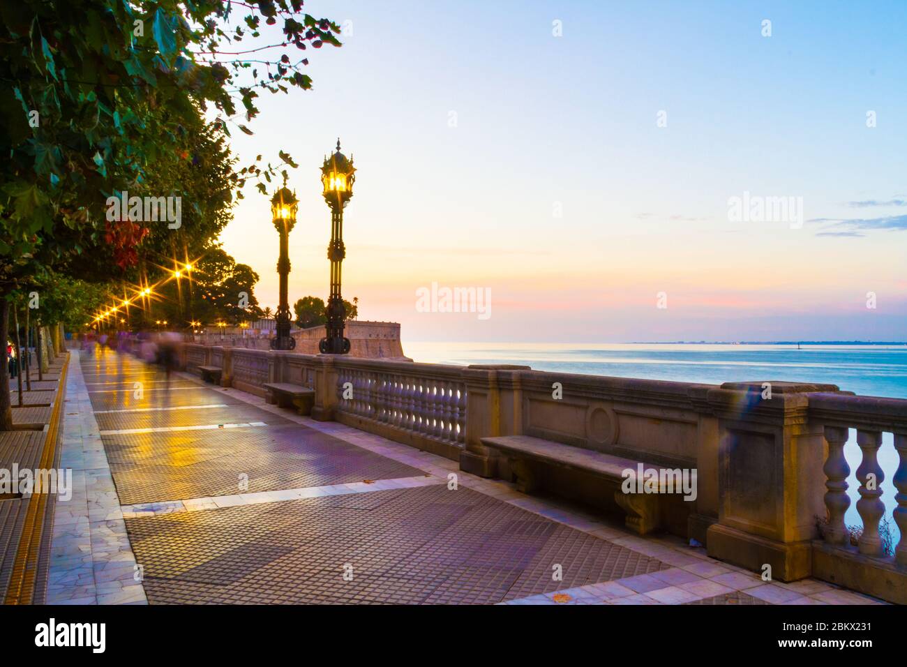 A colorful evening scene in a park in Cadiz, Spain with settle motion blurs of people and starburst in every street light. Stock Photo