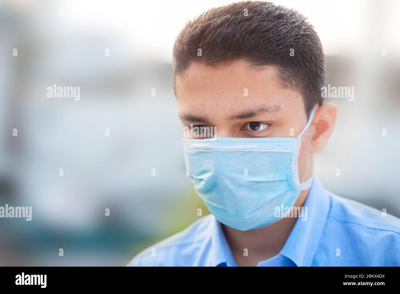 Portrait shot of a young man in blue colored shirt and wearing a ...