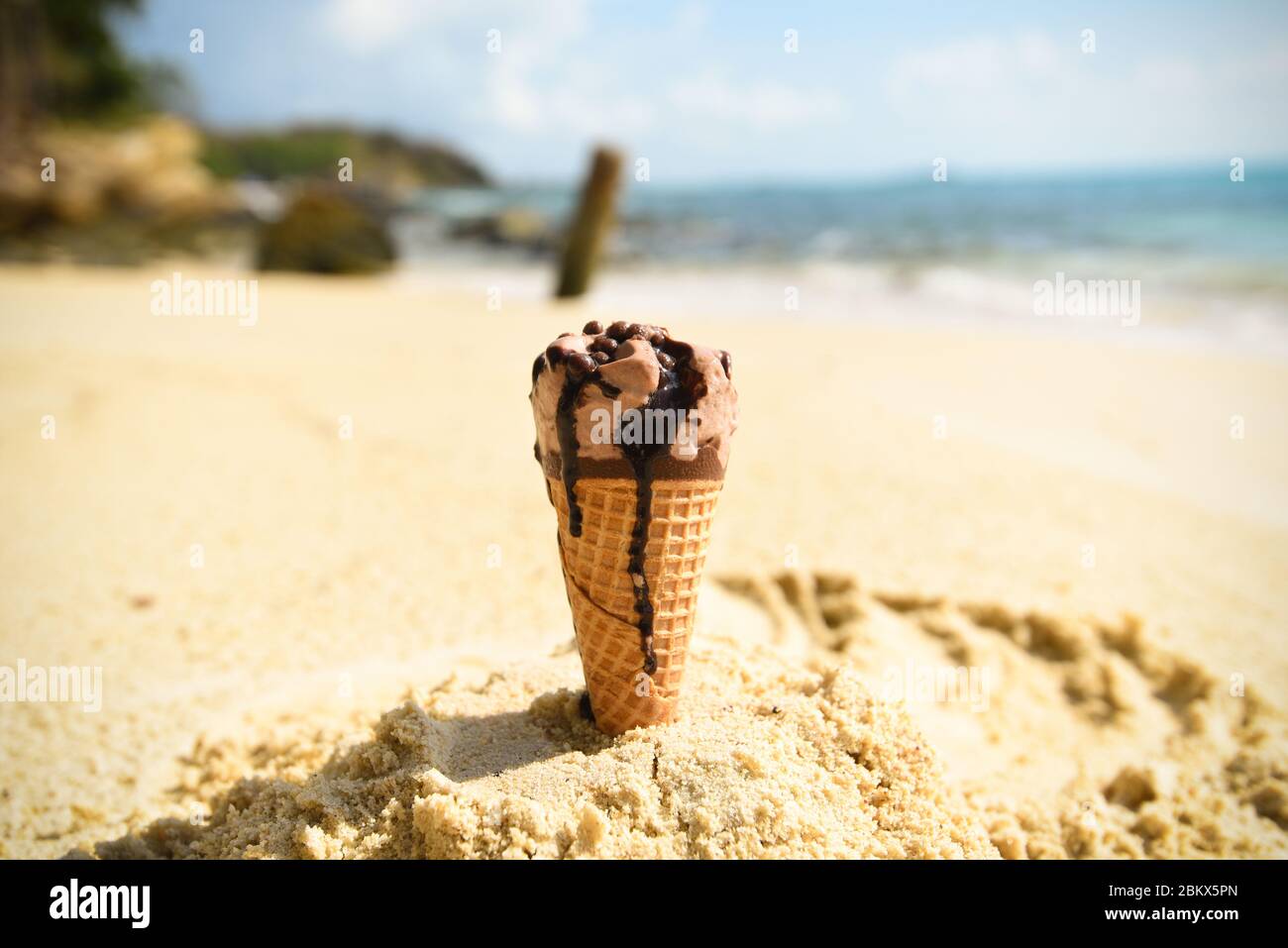 Ice cream cone on sand beach background / Melting ice cream on beach