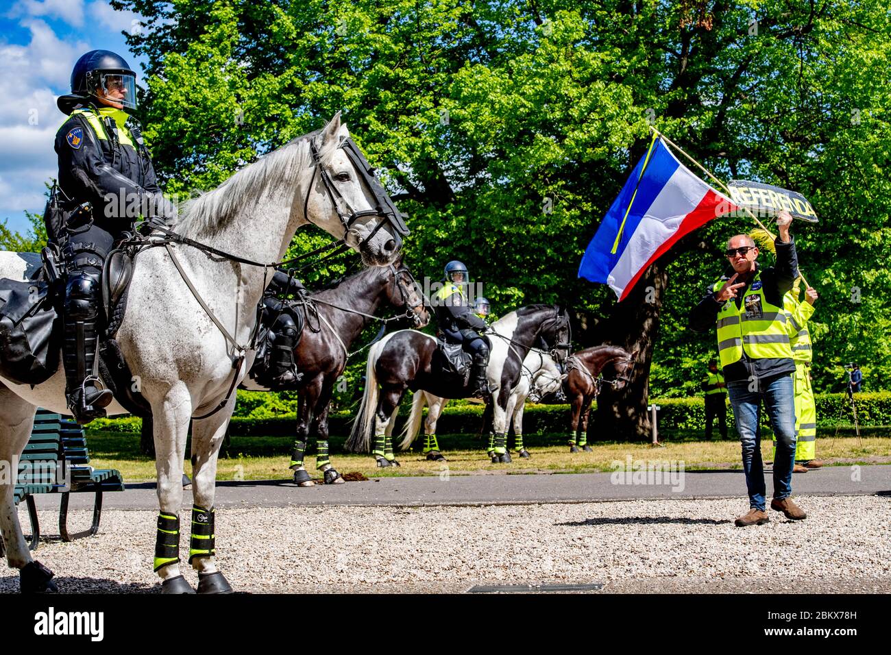 A demonstrator waving the Dutch flag as riot police looks on during the ...
