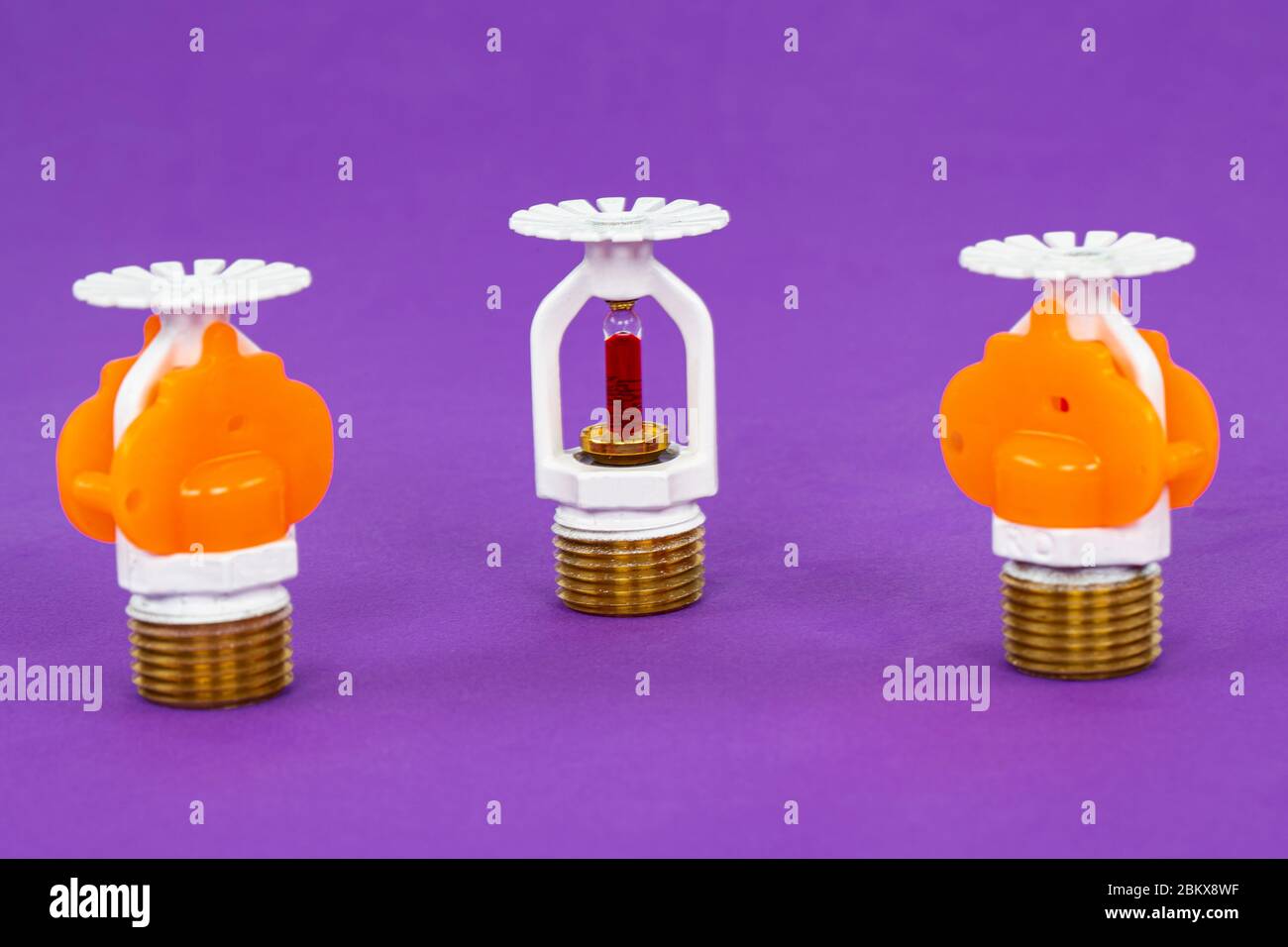 Close up image of fire sprinkler with fire in background. Fire