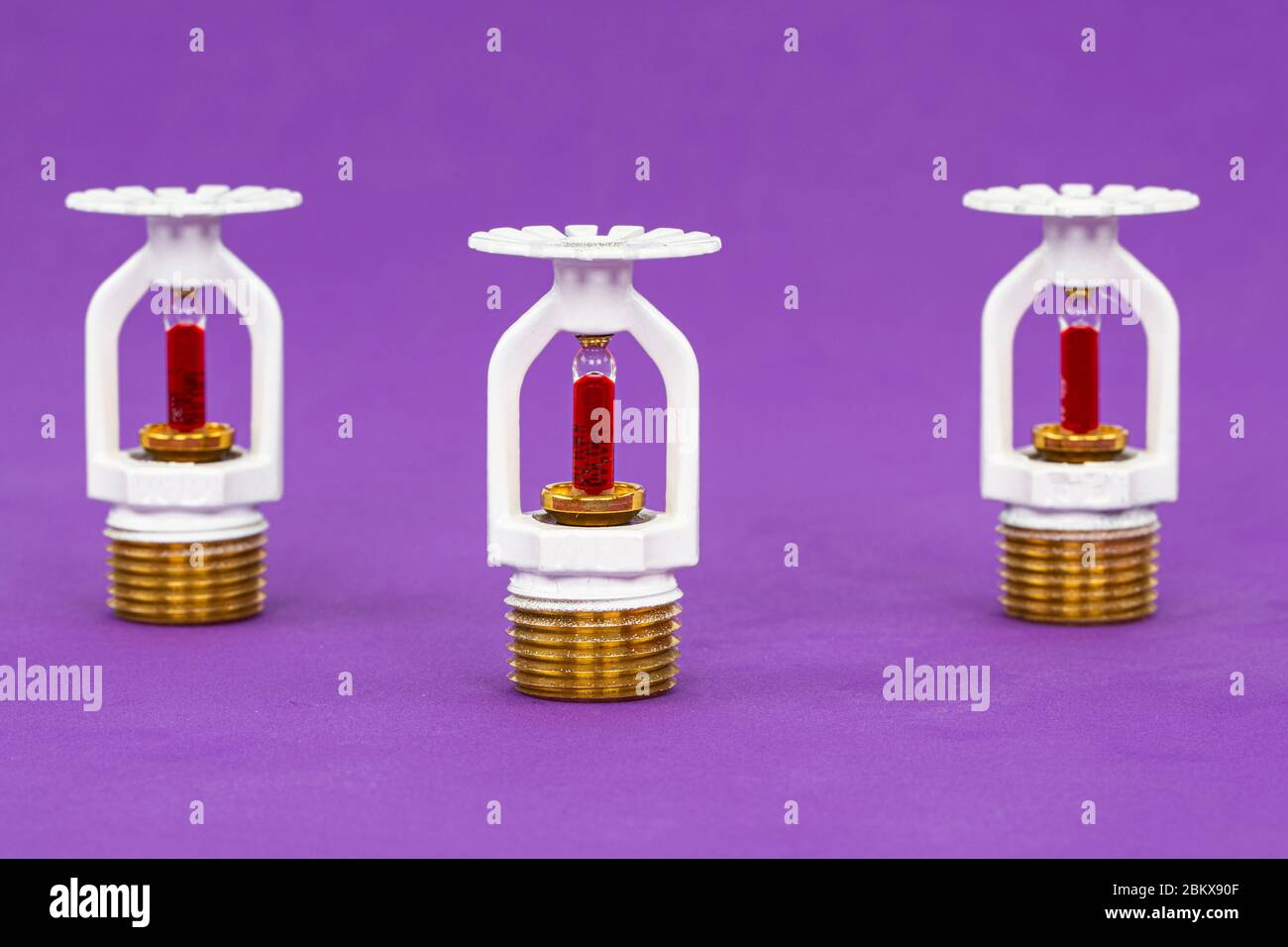 Close up image of fire sprinkler with fire in background. Fire