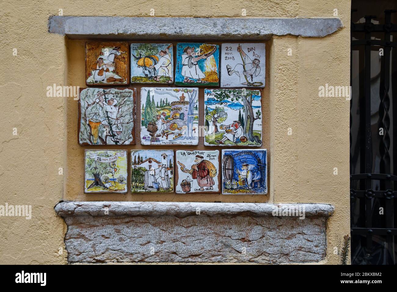 Hand-painted ceramic tiles by Sergio Vellini dedicated to the life of the friars on a wall in the historic center of Bardolino, Verona, Veneto, Italy Stock Photo