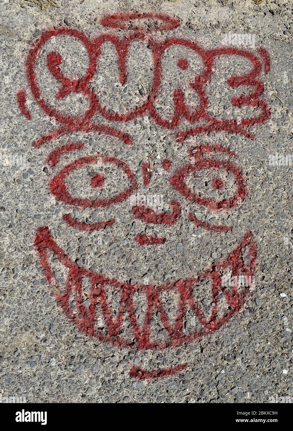 Graffiti of a face, halo and the word cure on the paved Old Alameda Creek trail in Union City, California Stock Photo