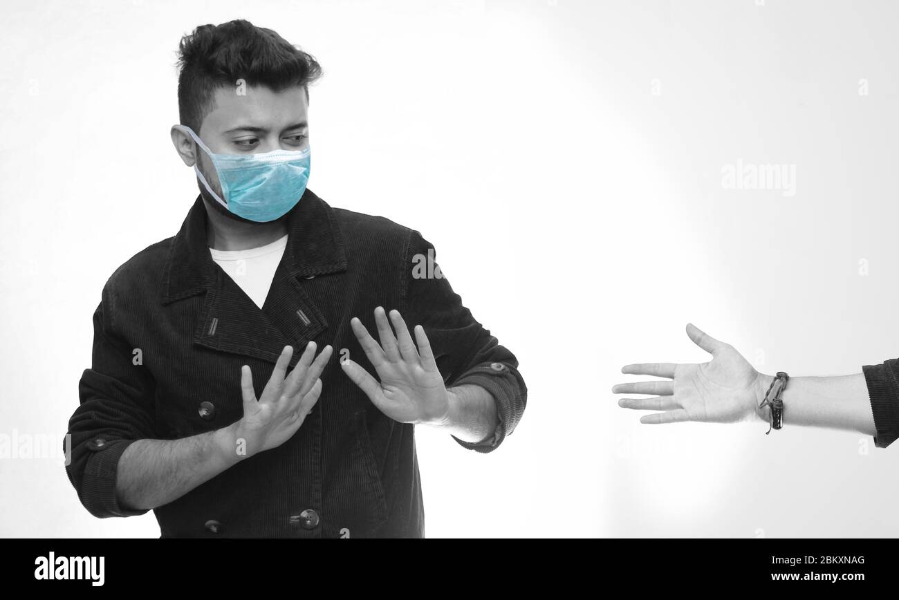 Social Distancing - Young Man Wearing Surgical Mask Avoiding Handshake For Safety And Protection During Coronavirus Pandemic - No Handshake Stock Photo
