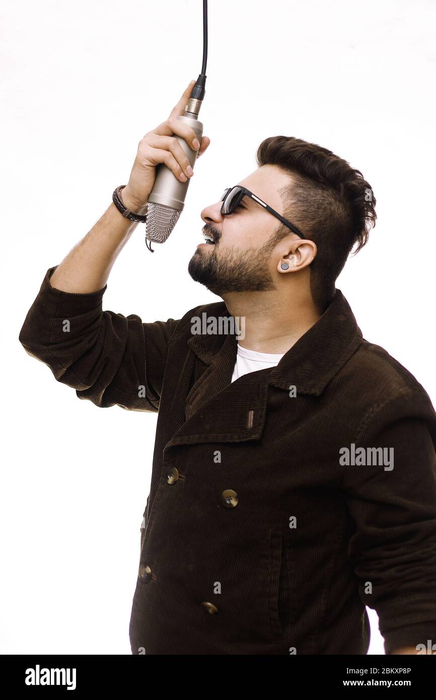 Talented young man wearing a brown coat and glasses coat singing a song in studio recording Stock Photo