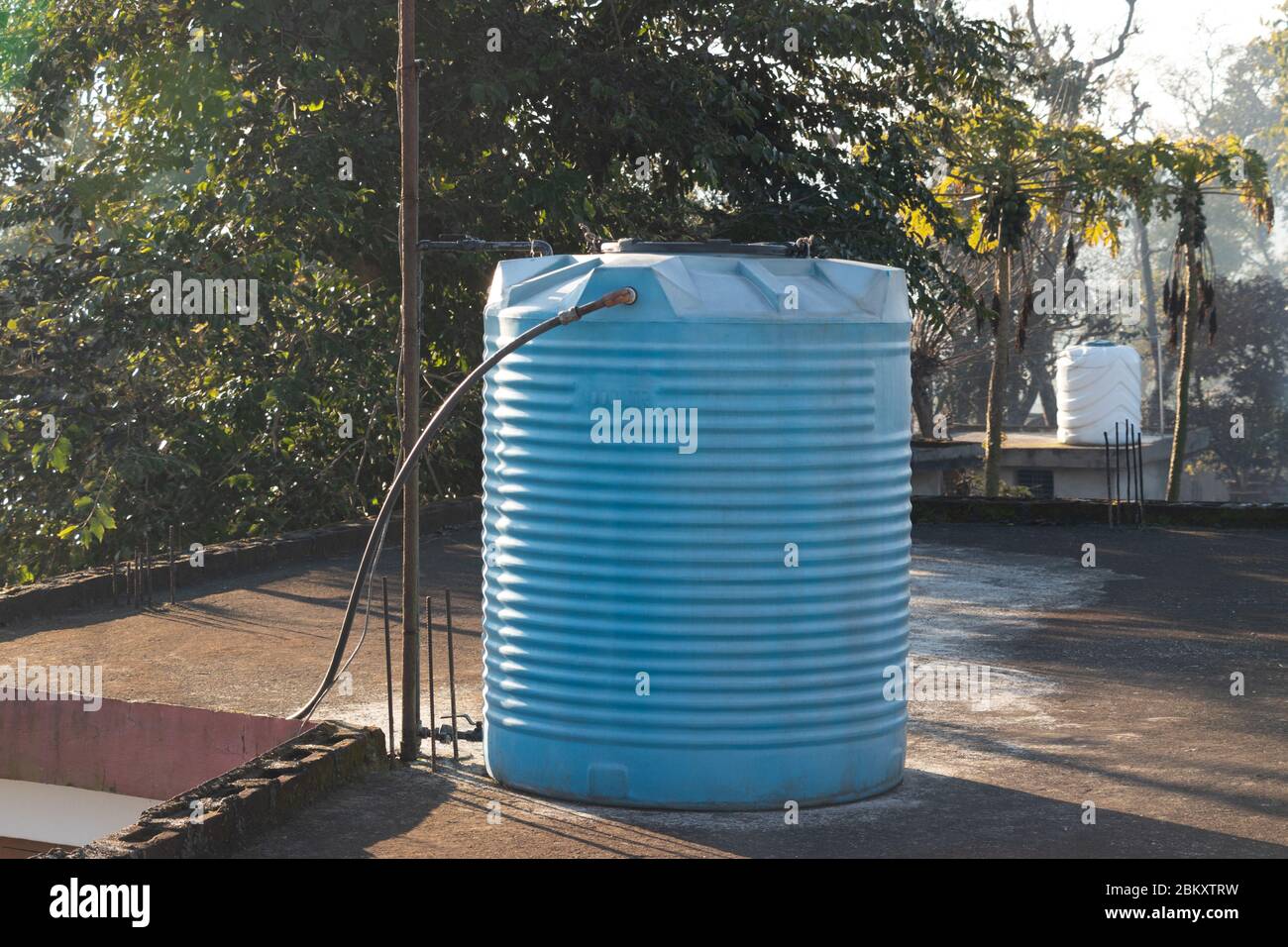 Blue water tank placed on the terrace of house connected with steel pipes. Stock Photo