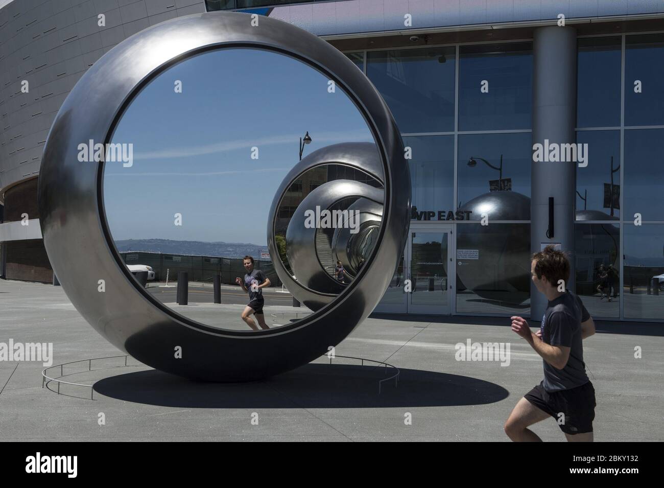 San Francisco, United States. 05th May, 2020. An unmasked runner passes the mirrored sculptures at Chase Center in San Francisco on Tuesday, May 5, 2020. The City is slow to ramp up business and has extended stay at home orders because of the coronavirus. Photo by Terry Schmitt/UPI Credit: UPI/Alamy Live News Stock Photo
