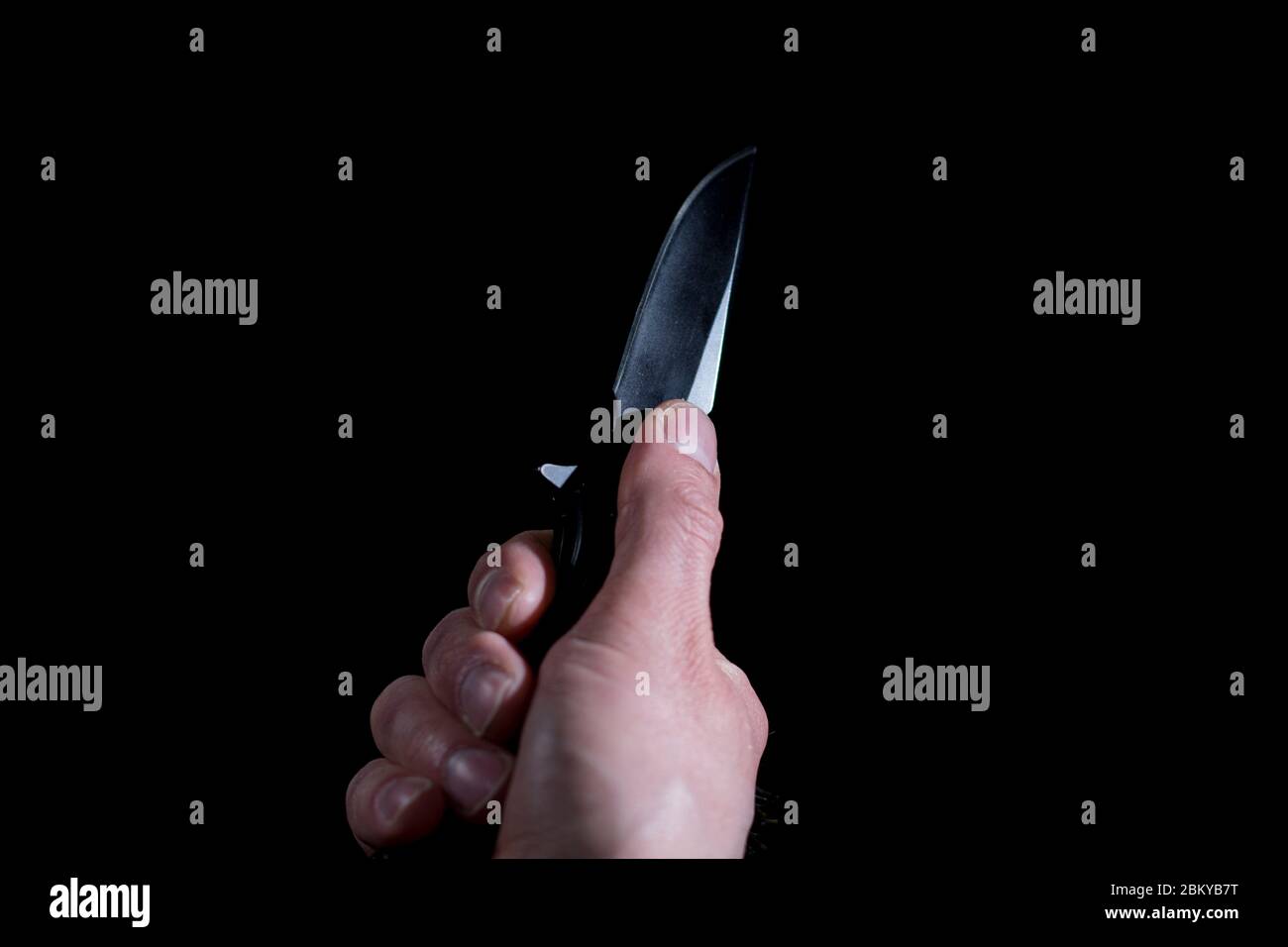 Switchblade knife in hand close up male robber holding black knife. Armed robbery concept. Close up of folding knife being opened. Hand held weapon. Stock Photo