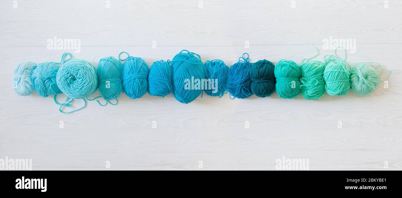 Yarn for knitting aquamarine, green, blue and turquoise colors. White wood long background Stock Photo