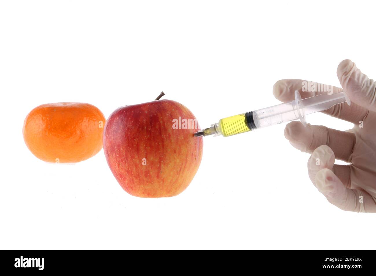 Injection into an apple. A hand in a medical glove with a syringe on a ...