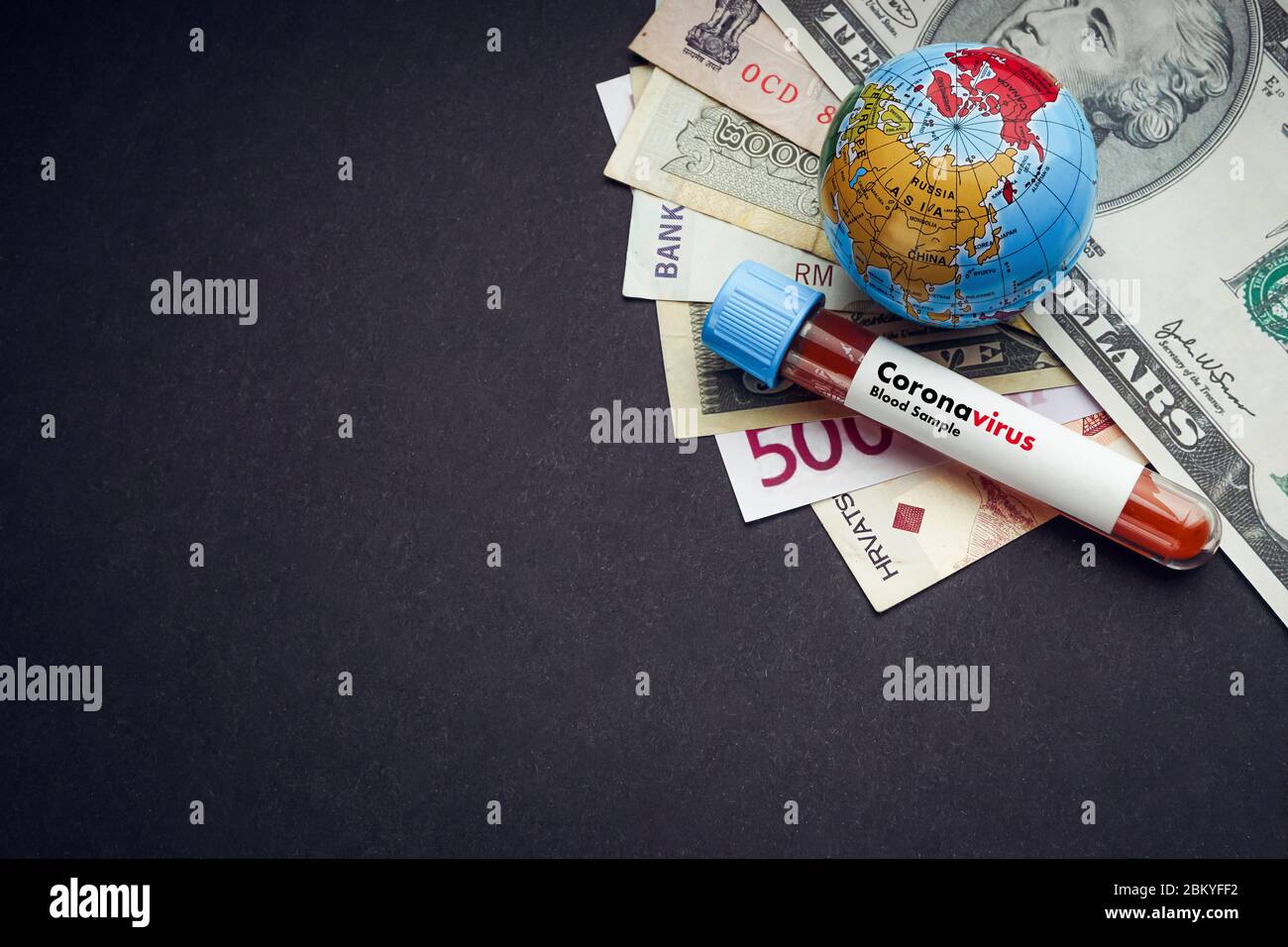 CORONAVIRUS text with currency banknotes, world globe and blood test vacuum tube on black background. Covid-19 or Coronavirus Concept. Copy space Stock Photo