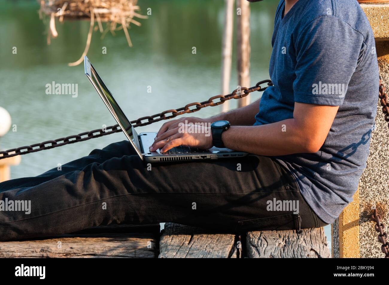 A man were blue shirt who working remotely by using laptop computer in the park. Stock Photo