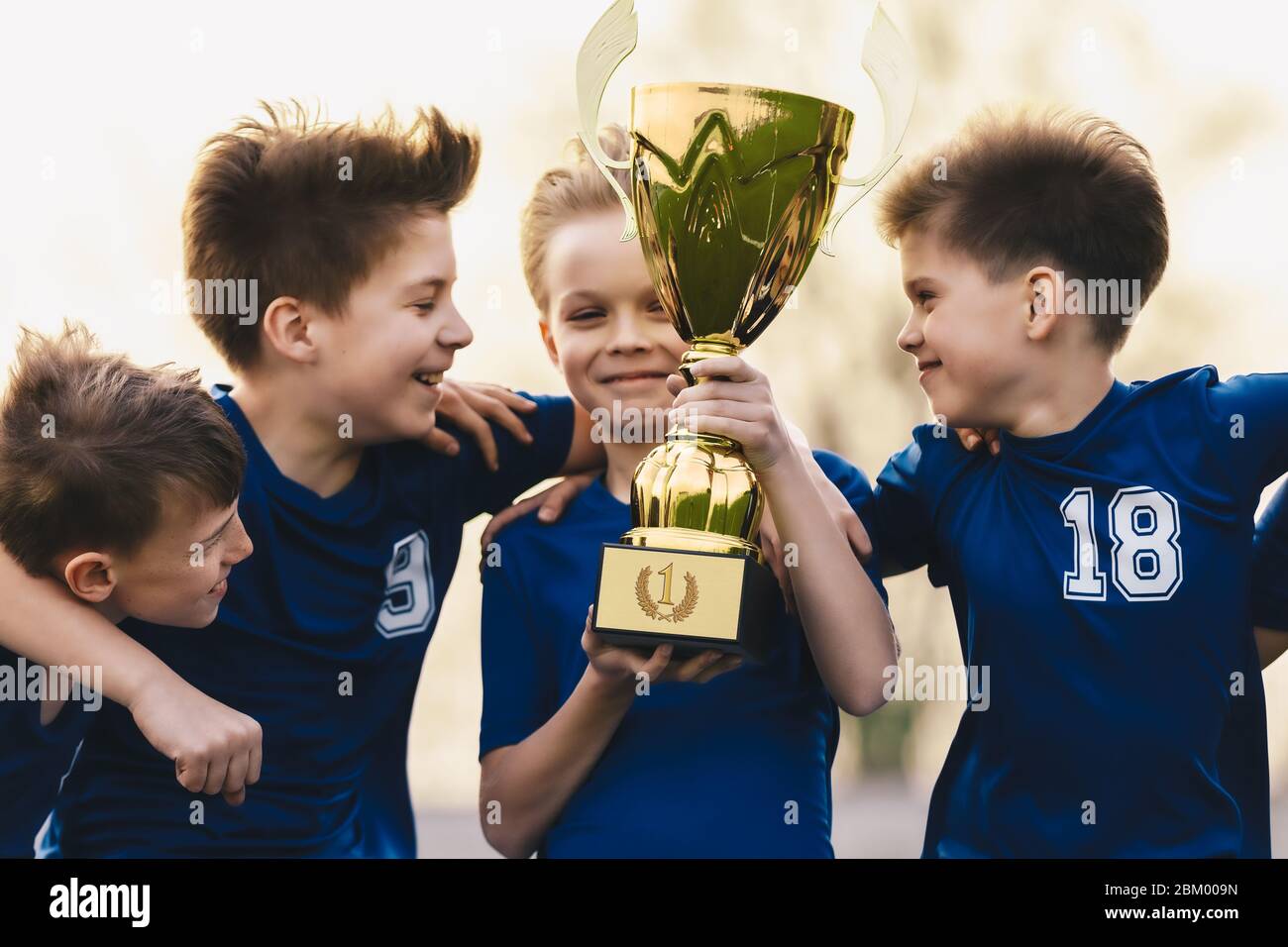 Happy Kids in Sports Team Celebrating Success in School Tournament. Young Caucasian Boys Holding Golden Trophy. Children in Youth Soccer Team Winning Stock Photo