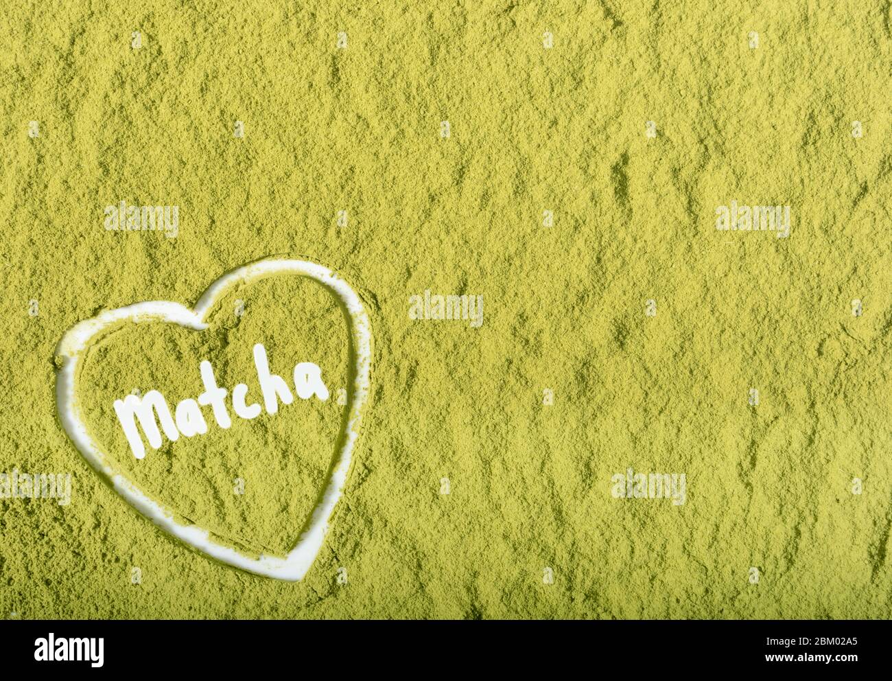 Matcha green tea powder textured scattered as background with heart ...
