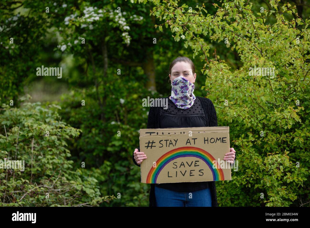 Young women holding cardboard sign placard stay at home save lives during coronavirus Stock Photo