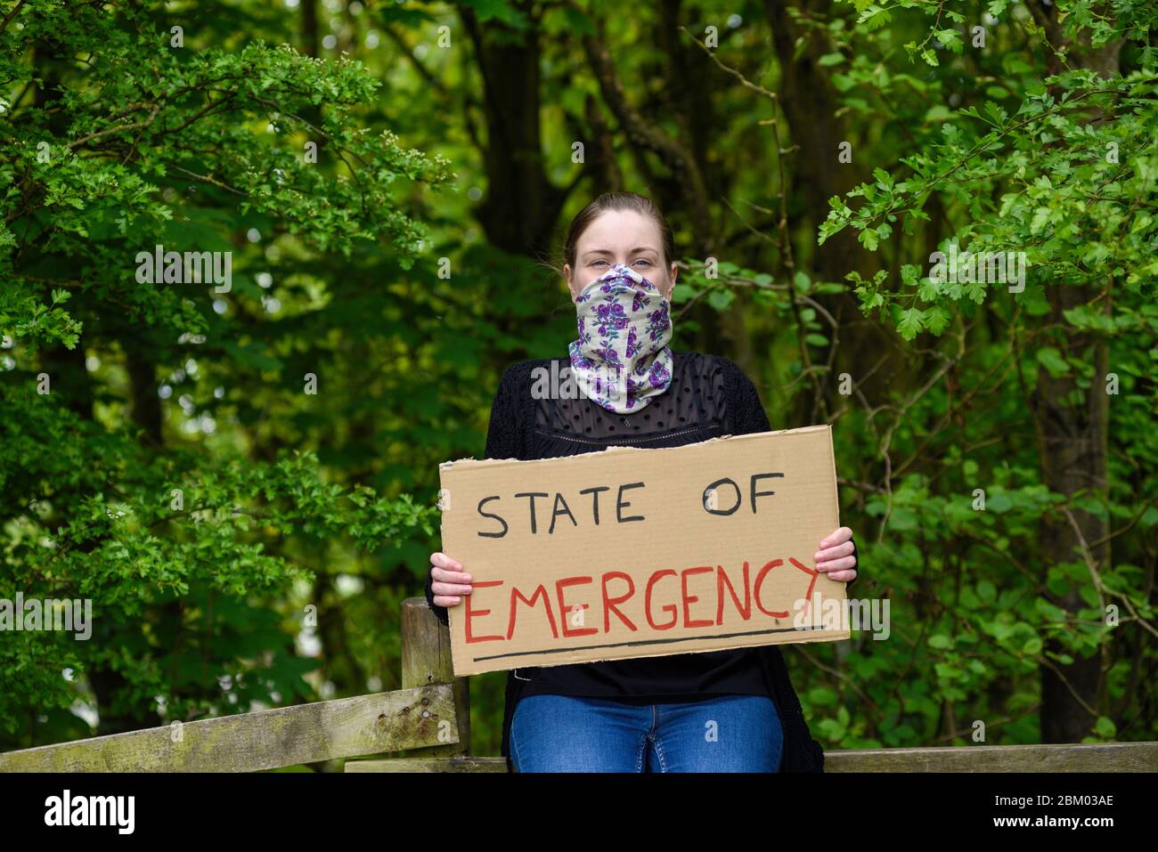 Young women holding cardboard sign placard state of emergency during Coronavirus pandemic. Stock Photo