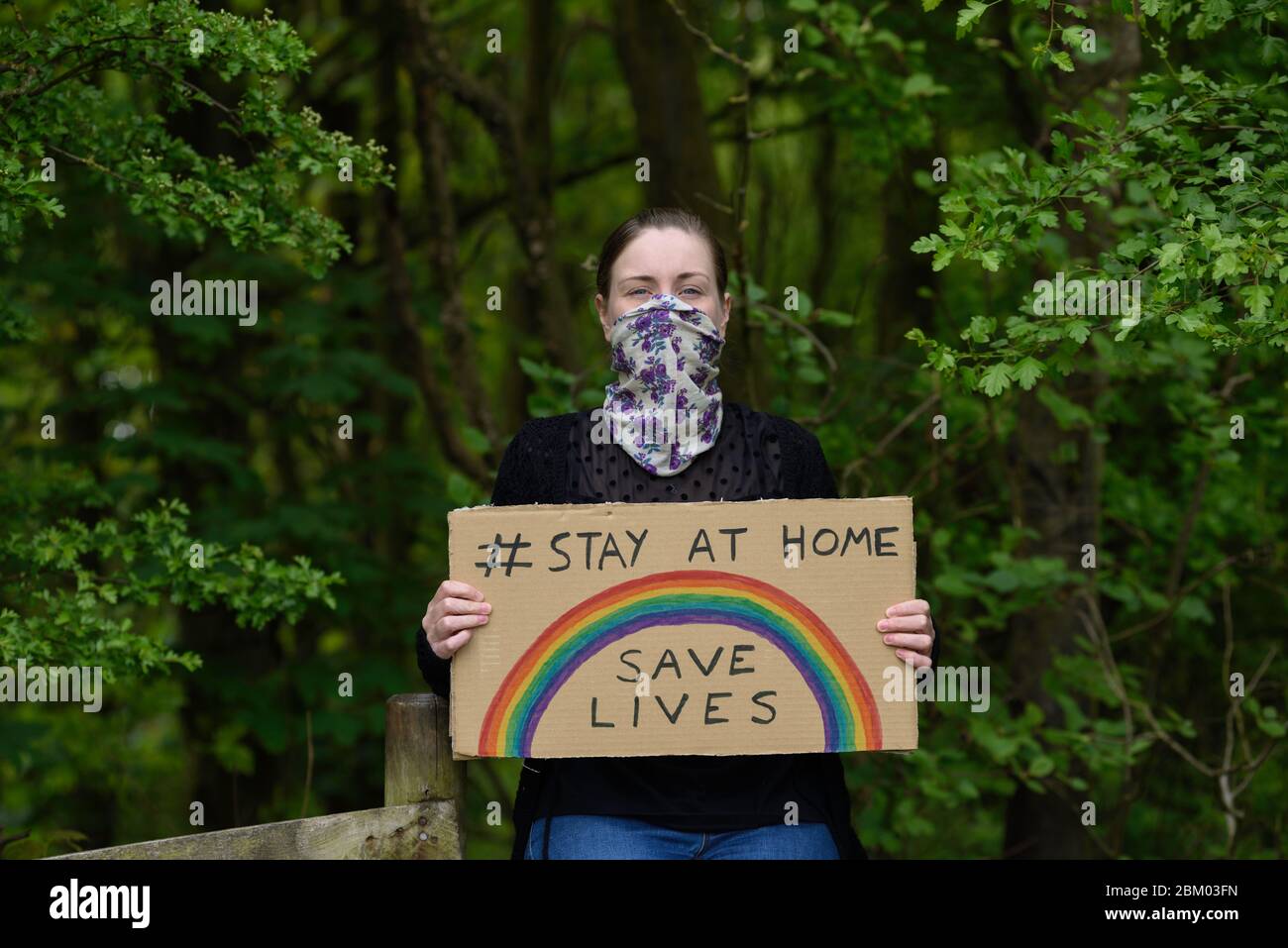 Young women holding a cardboard placard stay at home save lives during coronavirus pandemic. Stock Photo