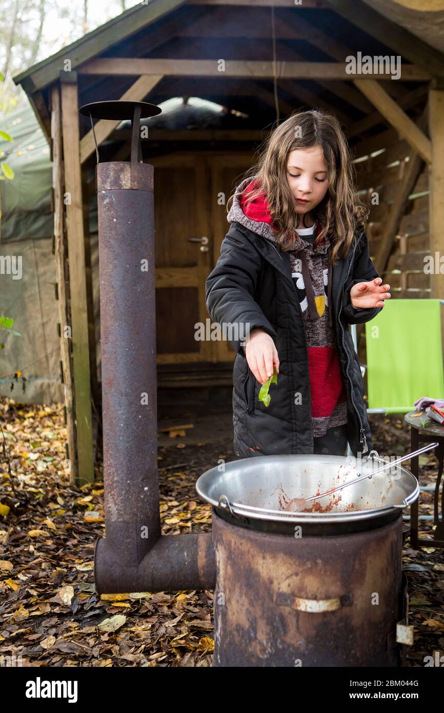 Young girl cooking outside on a wood fired Hungarian goulash oven kettle at a glamping family campsite Wowos in Sussex Stock Photo