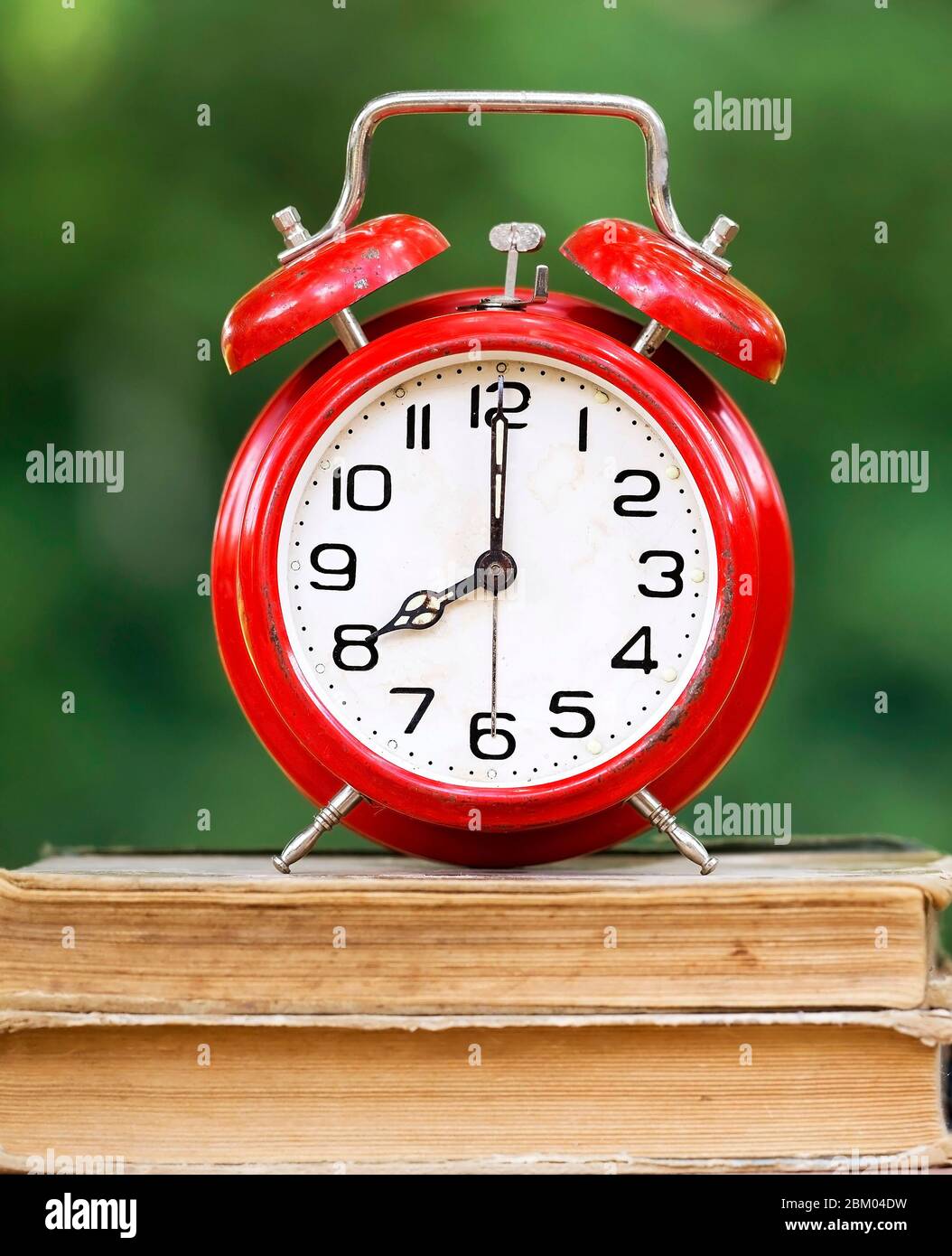 Retro red alarm clock standing on old books Stock Photo