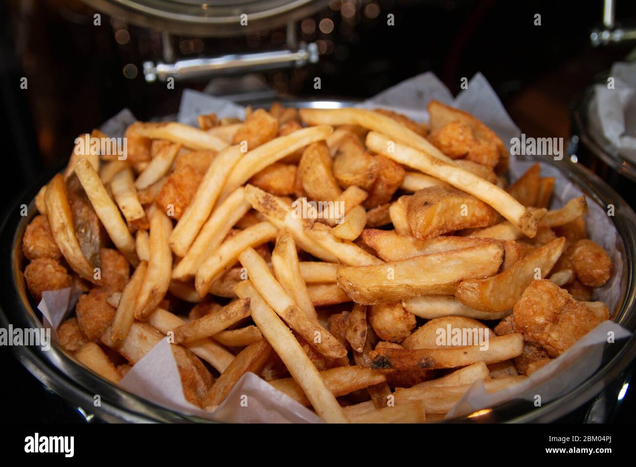 French fries and deep fried potato wedges mixed in a large buffet tray