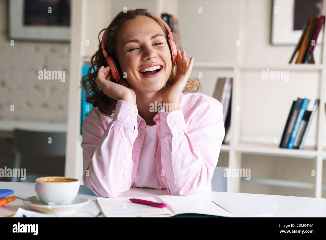 Photo of smiling nice woman using wireless headphones while doing ...