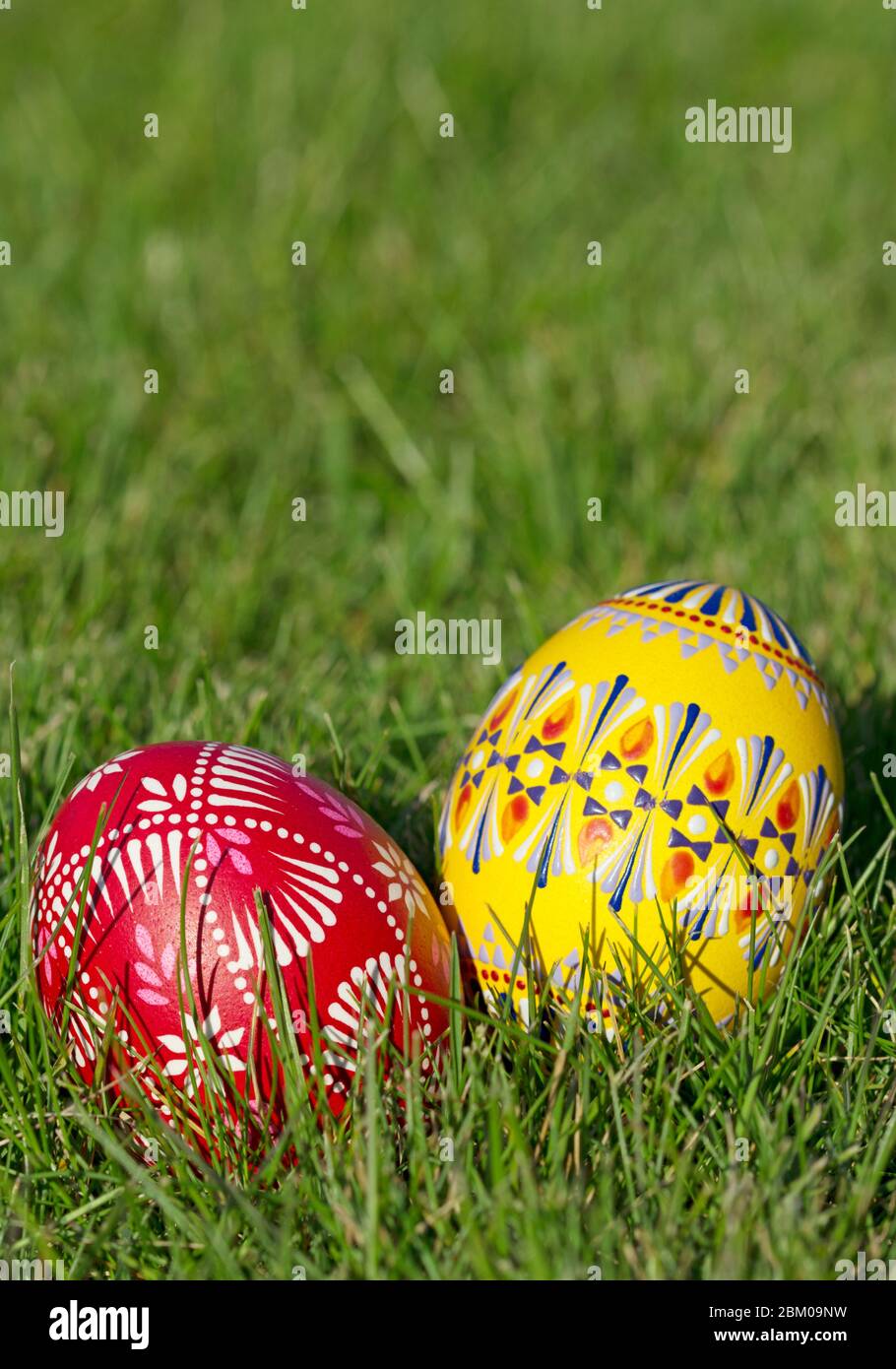 Two hand-painted Easter eggs lie in the grass in portrait format Stock Photo
