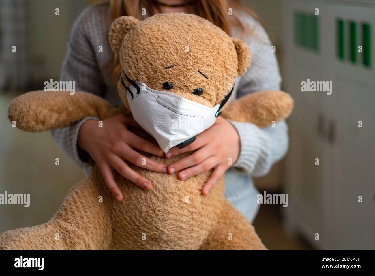 Teenage girl hugging teddy bear with face mask. Concept of corona virus, staying at home, isolation. Preventing flu virus Stock Photo