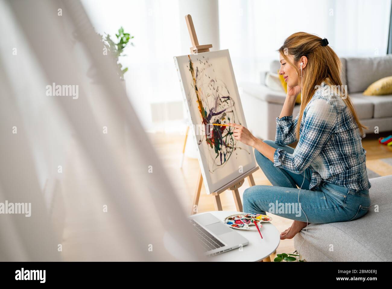 Beautiful woman painting on canvas at her home or workshop Stock Photo