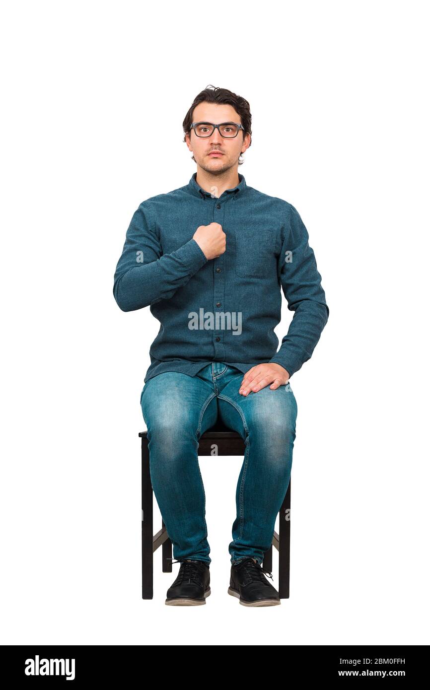 Full length portrait of perplexed businessman, seated on a chair  points index finger to himself, looking confused to camera isolated on white backgro Stock Photo