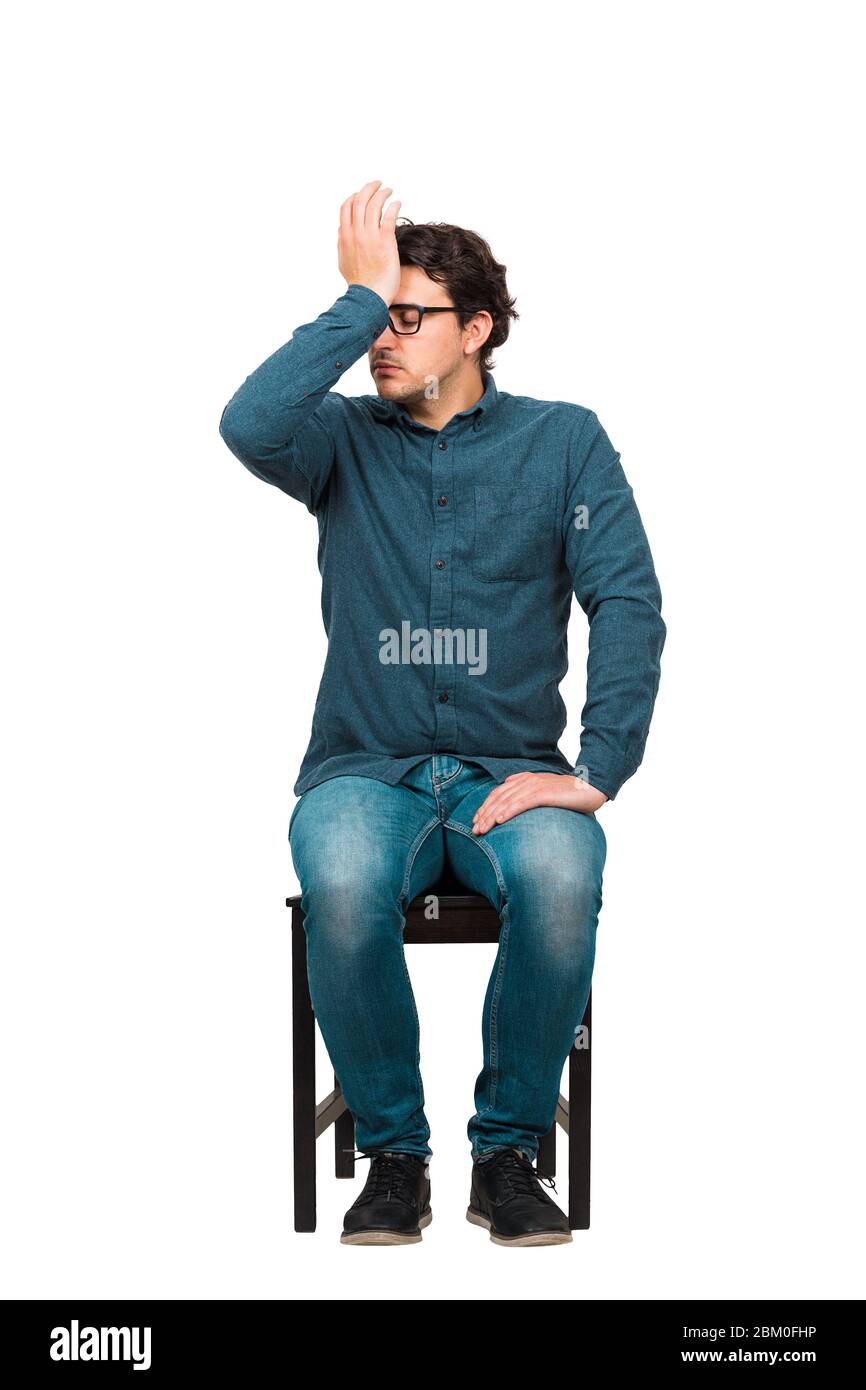 Full length of pessimistic businessman, eyes closed facepalm gesture, punching himself to forehead, seated on a chair isolated on white background. Di Stock Photo