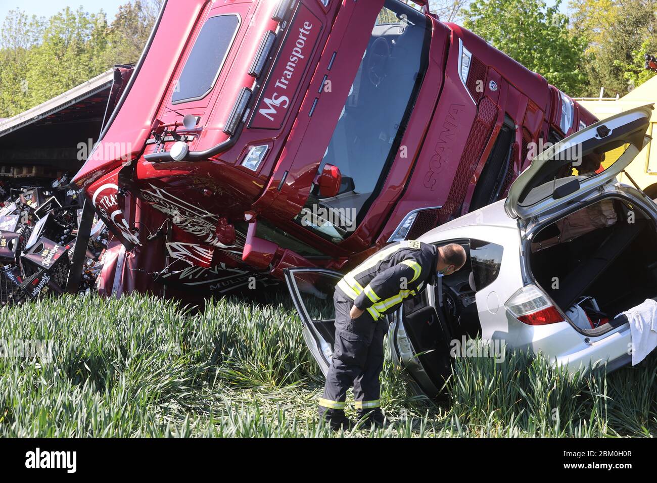 06 May 2020, Thuringia, Caaschwitz: Rescue workers are on the scene after a traffic accident. In the morning, a truck and a car had collided head-on. The truck loaded with full beer crates tipped over into an adjacent field. The driver of the car was seriously injured when he was flown by helicopter to a hospital. Photo: Bodo Schackow/dpa-zentralbild/dpa Stock Photo