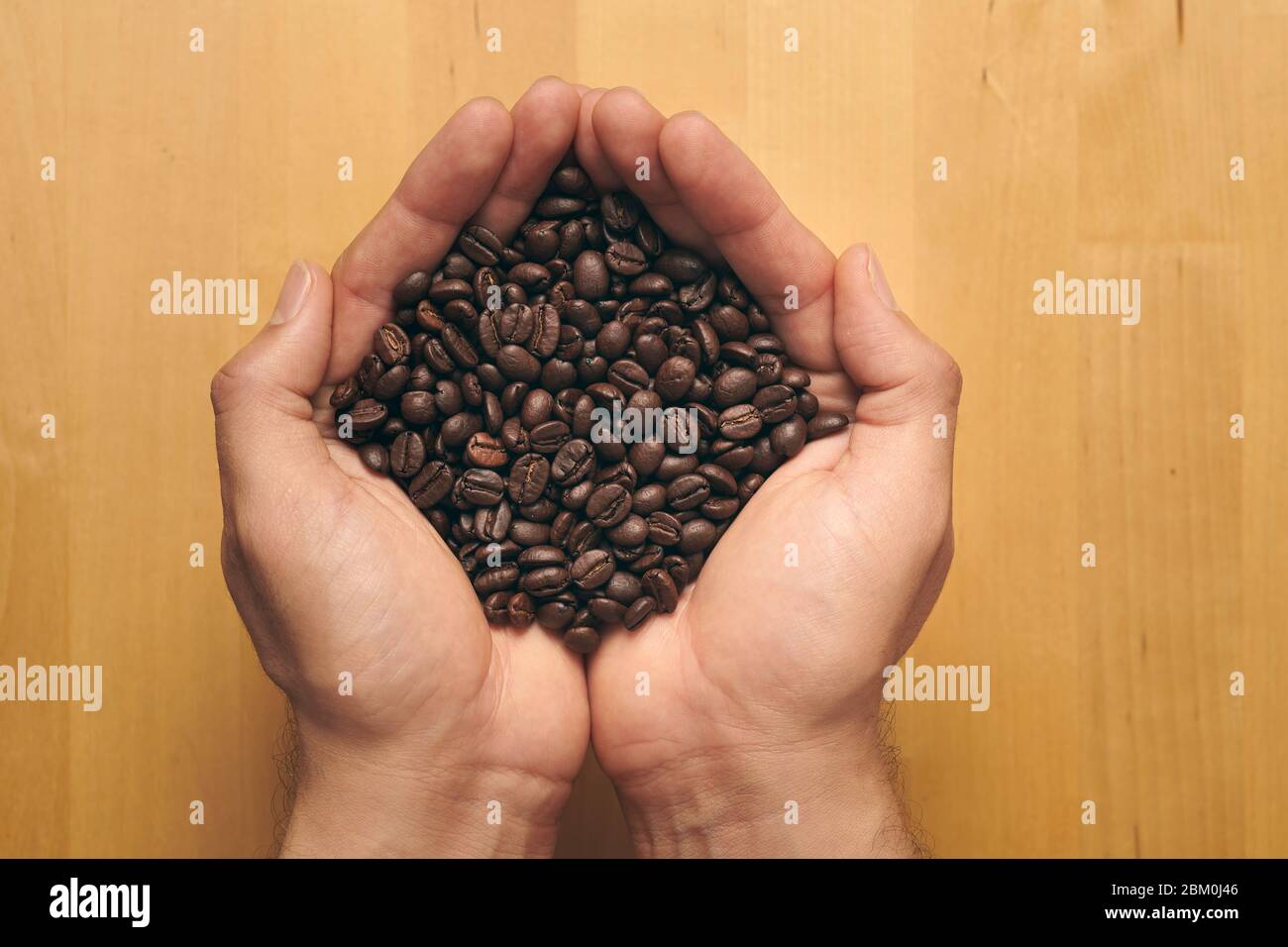 Handful of freshly ground coffee beans on a wooden background Stock Photo
