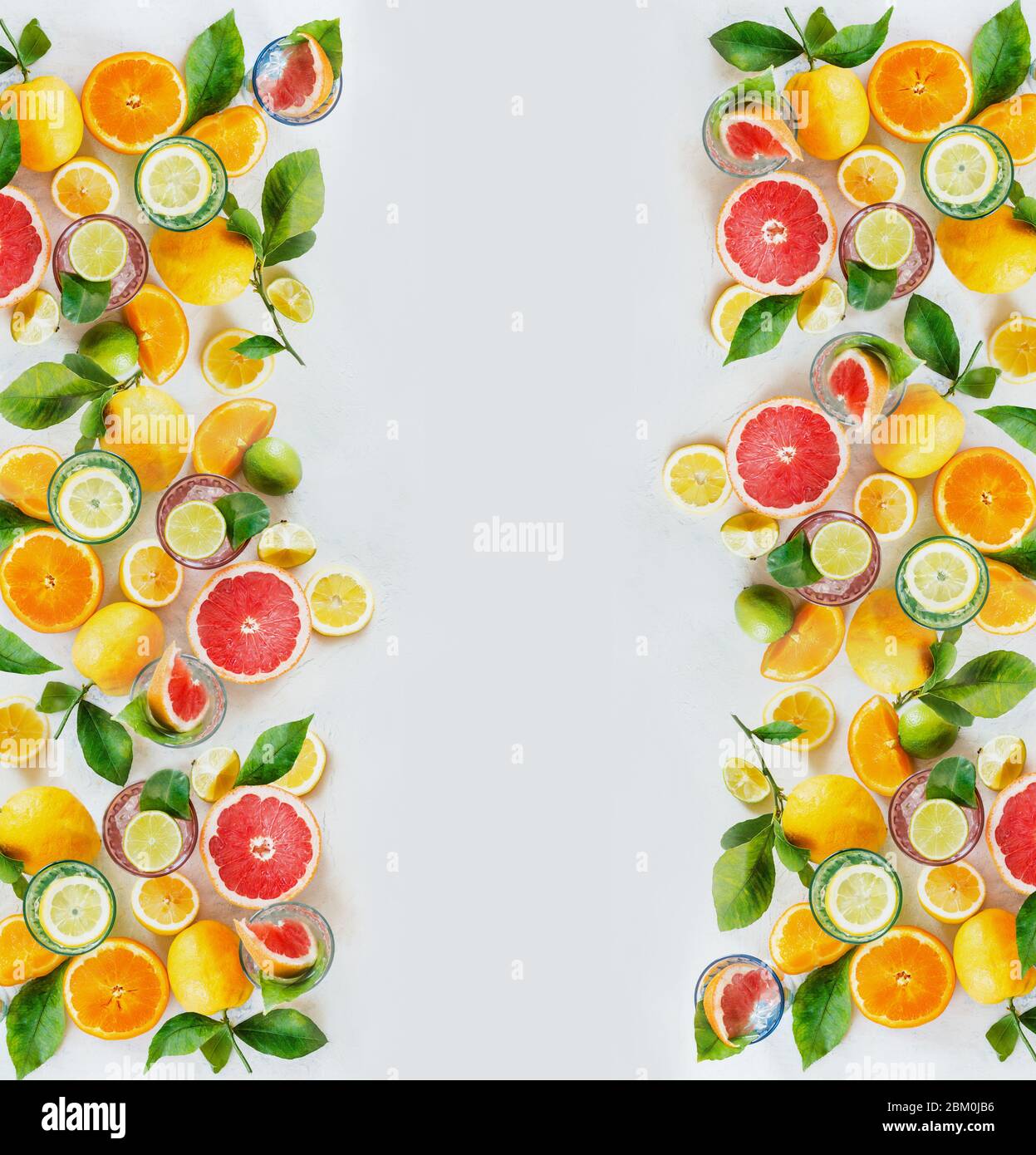 Frame of various colorful citrus fruits: lemon, lime, orange and grapefruit with green leaves and glasses of refreshing lemonade drinks on white backg Stock Photo