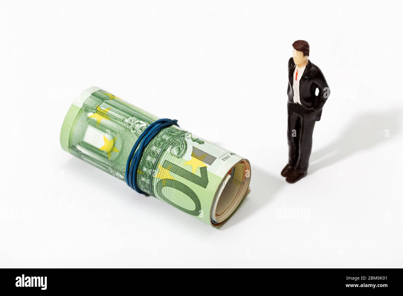 Human representation of a man looking at a Roll of money. Finance, investment or savings concept Stock Photo