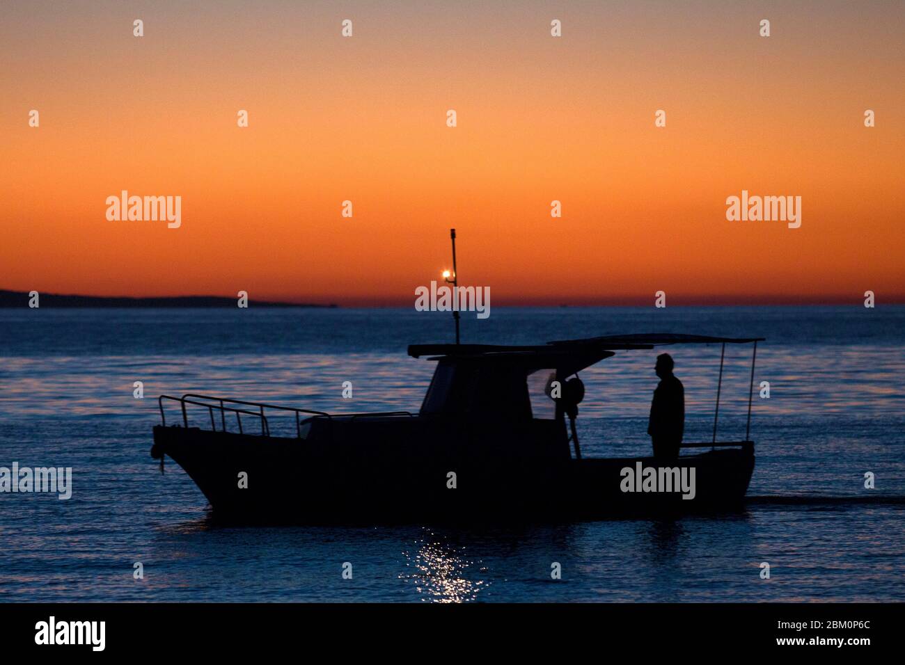 Silhouette of a fishermen sailing in the sunset Stock Photo - Alamy