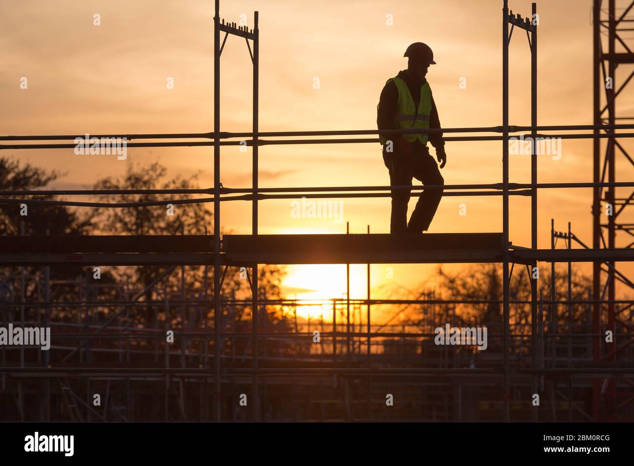 worker on scaffolding at sunset Stock Photo