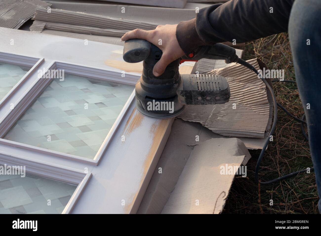 master processes wooden doors with a grinding tool, restoration