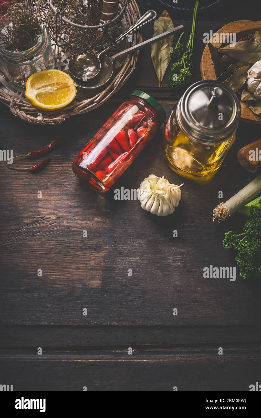 Food background with pickled vegetables, jar with olives oil, herbs and spices on dark kitchen table. Top view. Home cuisine. Tasty cooking and preser Stock Photo