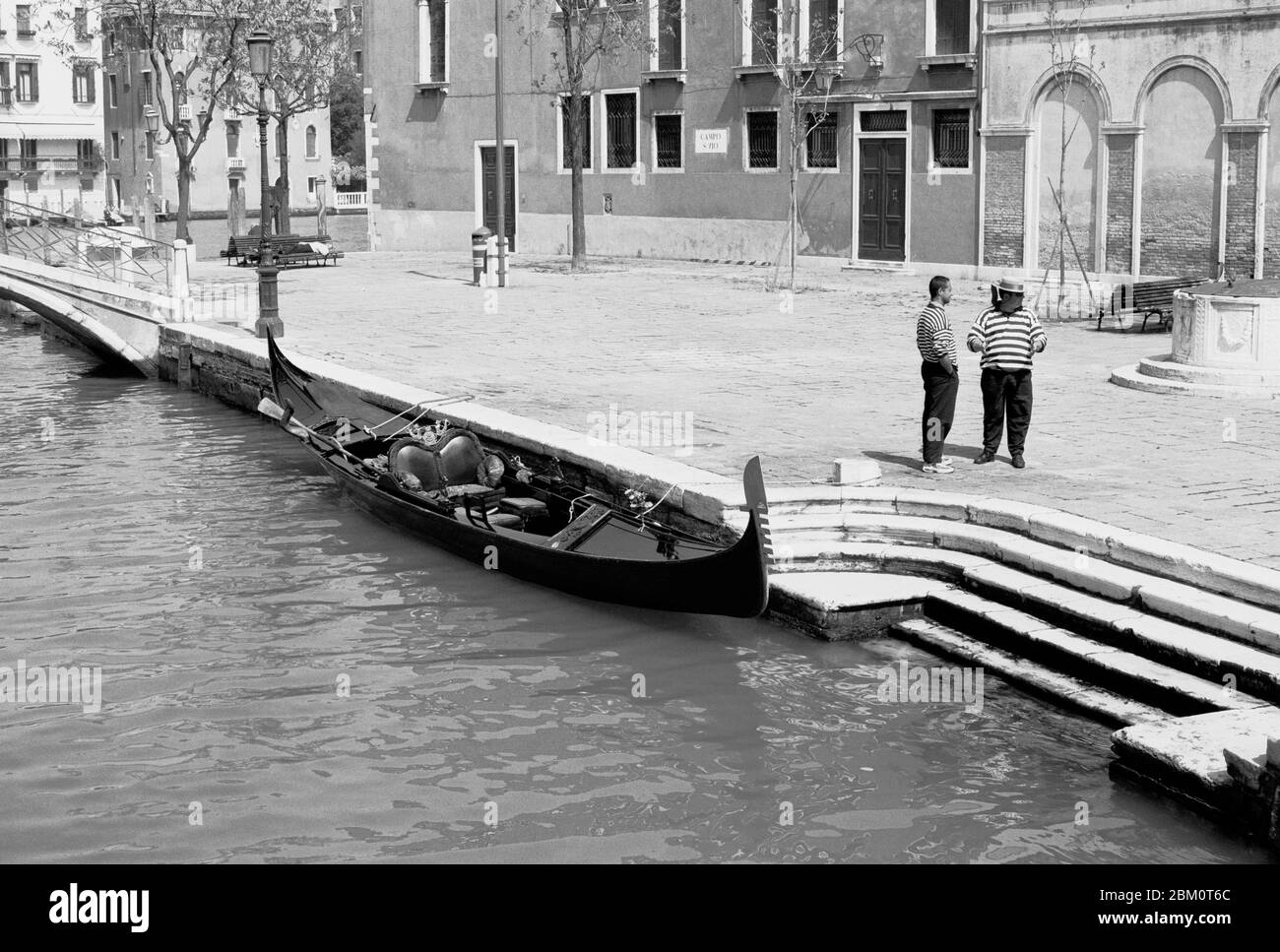 GONDOLIERI AND HIS GONDOLA EXPECTING PASSENGERS ON ONE OF THE CANALS OF THE CITY - VENICE ITALY - VENEZIA ITALIA - VENICE CLASSIC - SILVER PHOTOGRAPHY © Frédéric BEAUMONT Stock Photo