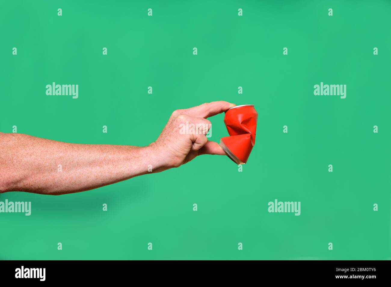 hand crushing a tin can on green background Stock Photo Alamy