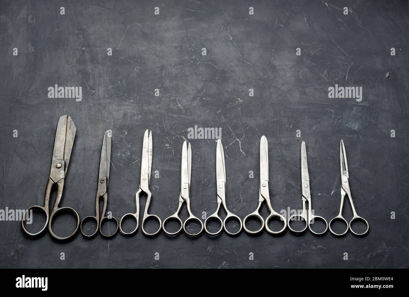 Many different scissors on dark background. Minimal black. Flat lay Stock Photo