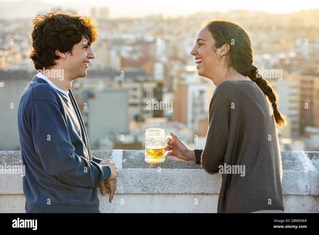 Young couple chatting and having a beer on the terrace Stock Photo