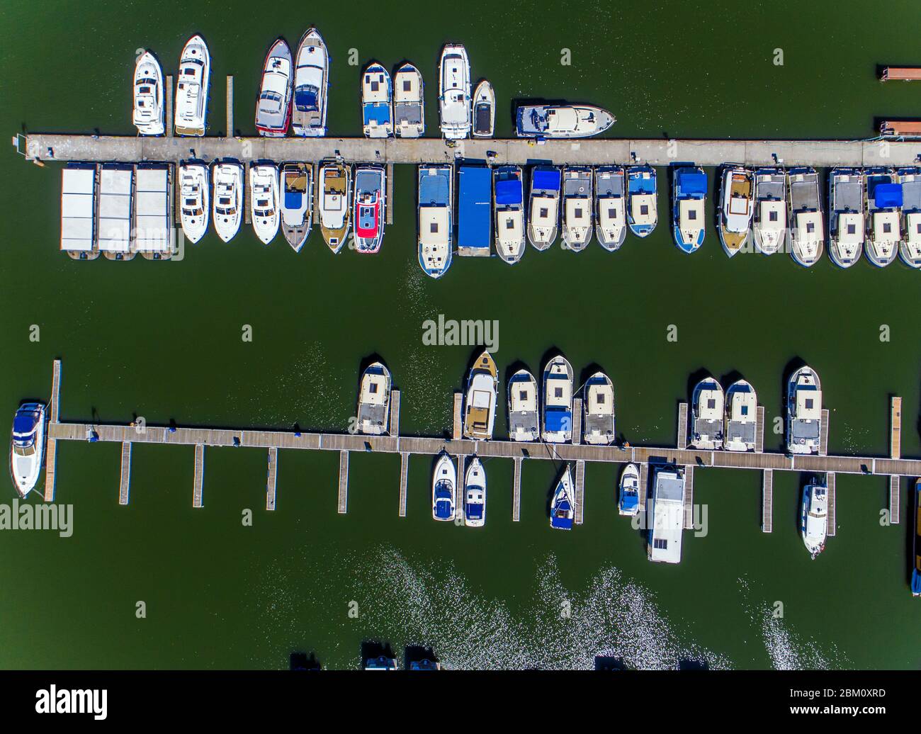 Rechlin, Germany. 06th May, 2020. Houseboats, which are not allowed to be rented because of corona protection measures, are moored at the landing stage of the company Kuhnle-Tours at the Müritz (aerial view with a drone). The tourism enterprises at the Mecklenburg Lake District prepared for loosening of the corona restrictions. According to the rental company, it is not yet clear when houseboats may be rented out again. Credit: Jens Büttner/dpa-Zentralbild/dpa/Alamy Live News Stock Photo