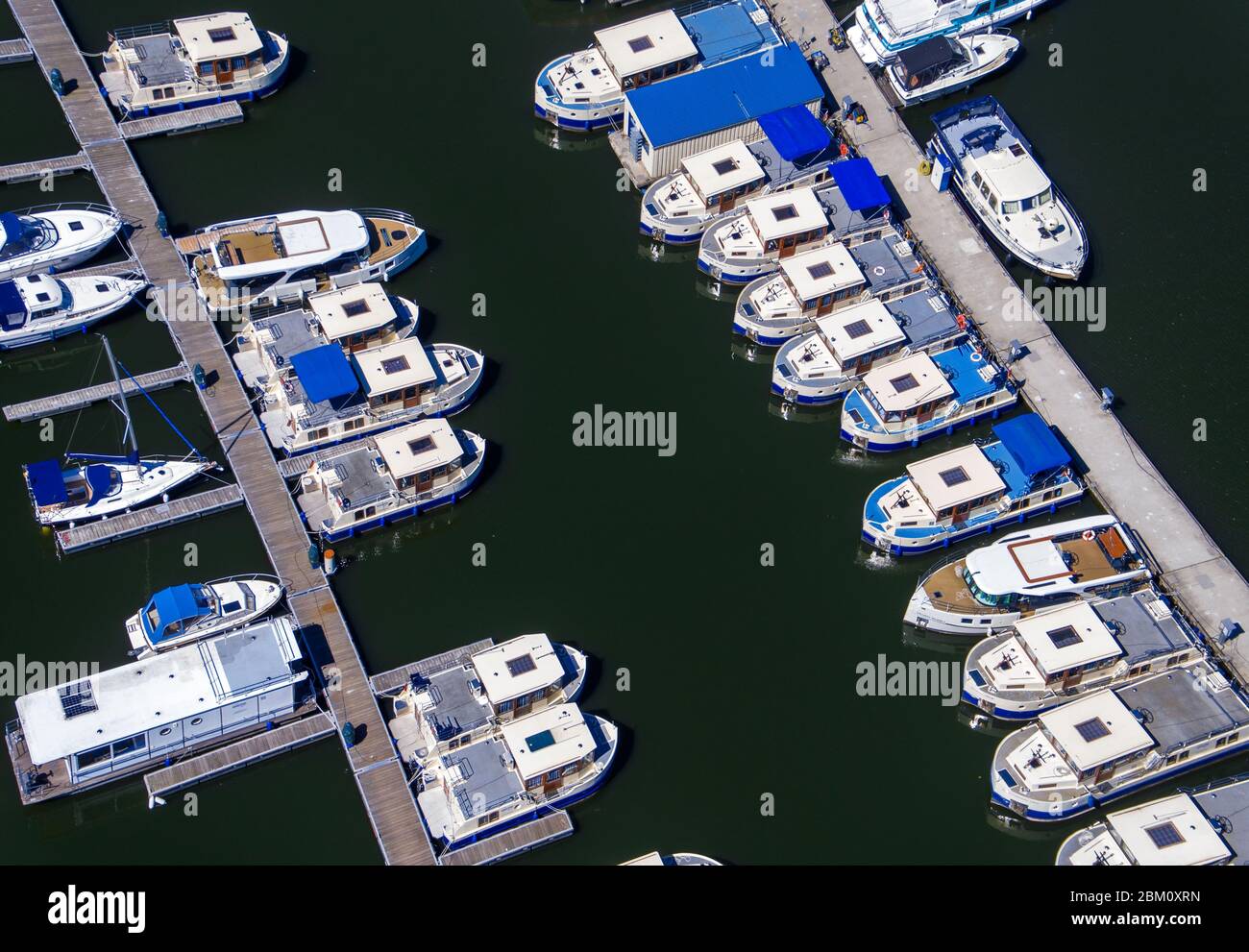 Rechlin, Germany. 06th May, 2020. Houseboats, which are not allowed to be rented because of corona protection measures, are moored at the landing stage of the company Kuhnle-Tours at the Müritz (aerial view with a drone). The tourism enterprises at the Mecklenburg Lake District prepared for loosening of the corona restrictions. According to the rental company, it is not yet clear when houseboats may be rented out again. Credit: Jens Büttner/dpa-Zentralbild/dpa/Alamy Live News Stock Photo